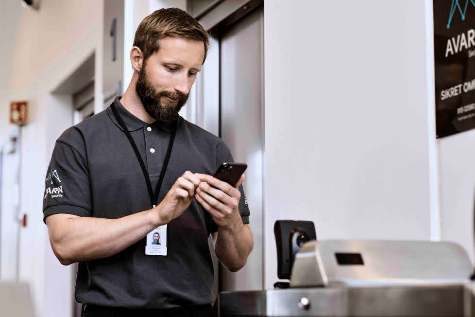 Vekter som holder en telefon i hånda og ser på den